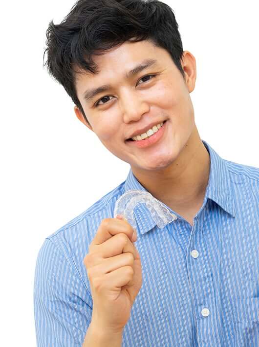 young man holding up an Invisalign clear aligner set