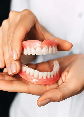 closeup of a person holding a set of dentures in their hand