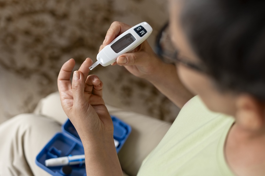 woman with diabetes checking blood sugar, which can affect oral health, gum disease, dry mouth, dental care, Dallas Center for Oral Health & Wellness