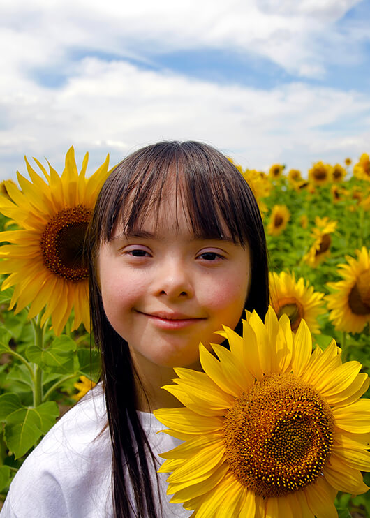 young girl with autism standing in a field of sunflowers